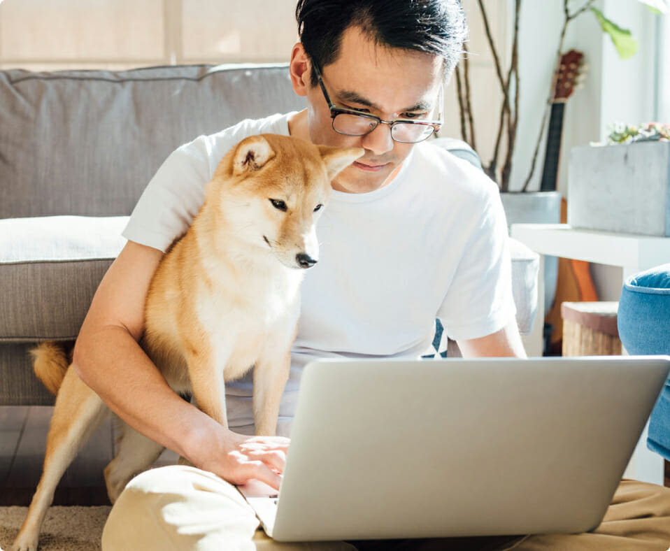 Man using laptop to work on continuing education courses with dog in his lap.
